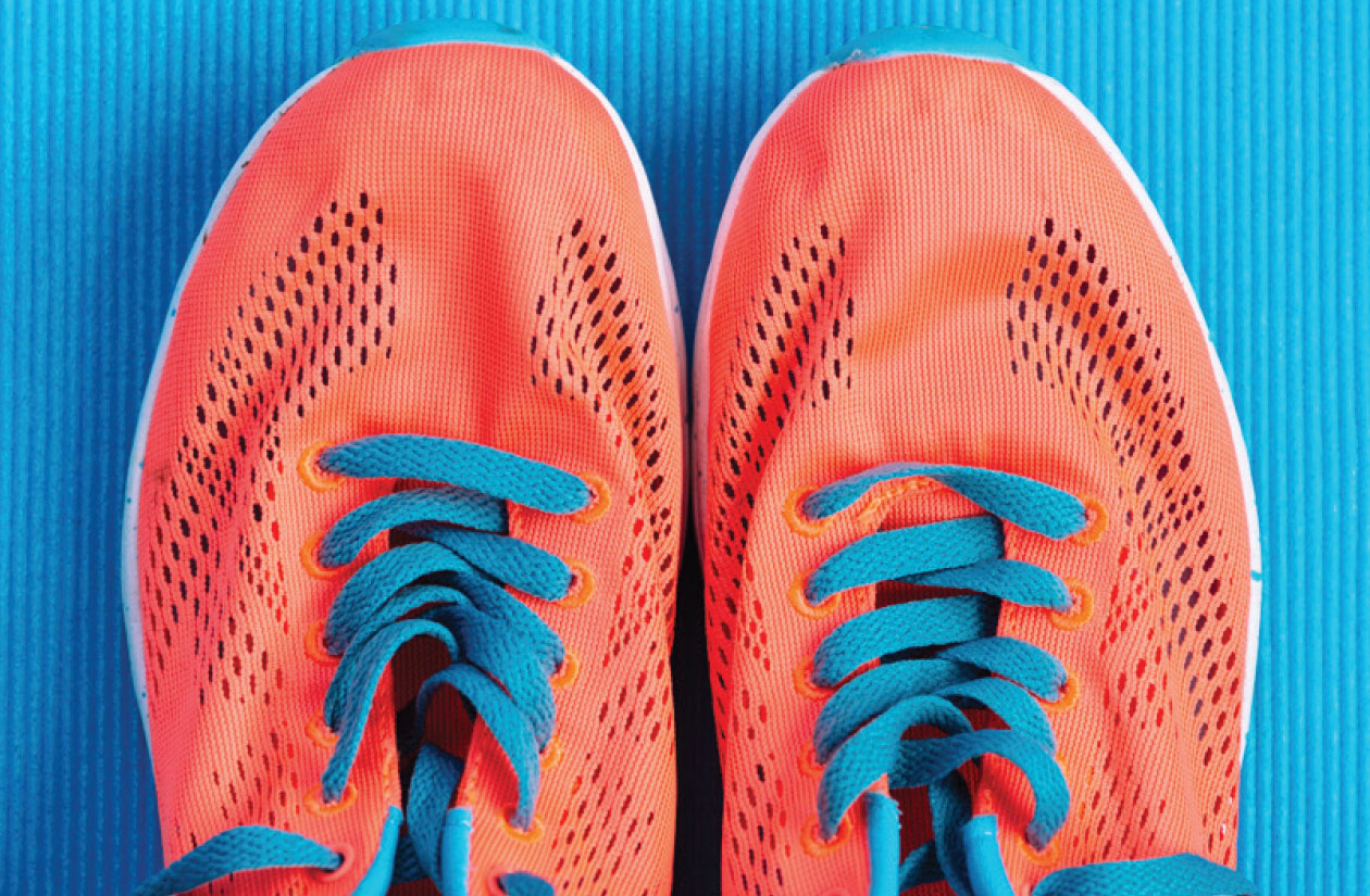 Orange running shoes with turquoise laces on a blue mat.