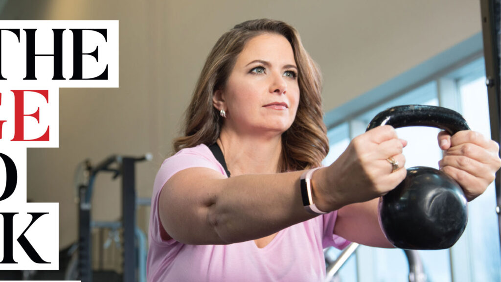 Woman holding a kettlebell forward at shoulder height in a gym beside partially cropped headline lettering.