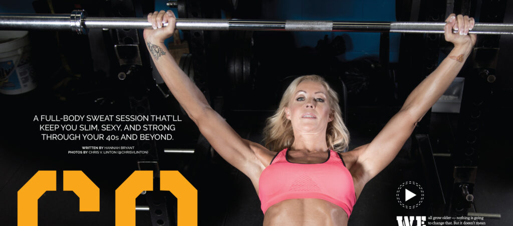 Woman in a pink sports bra lifting a barbell overhead in a gym setting.