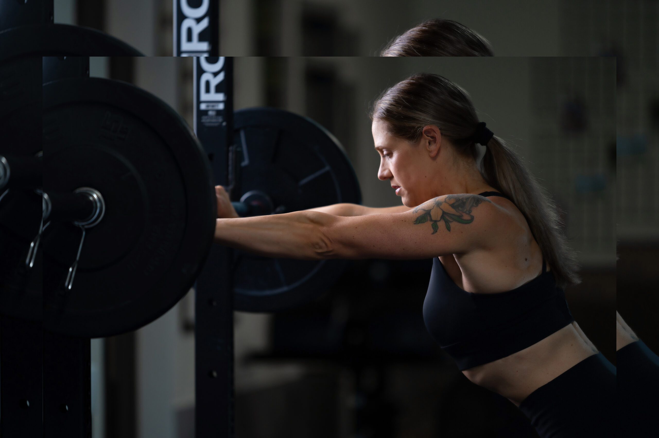 Woman leaning forward with her arms extended against a racked barbell.