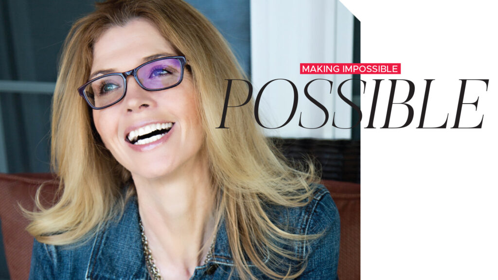 Smiling woman wearing glasses beside the heading “Making Impossible Possible”.