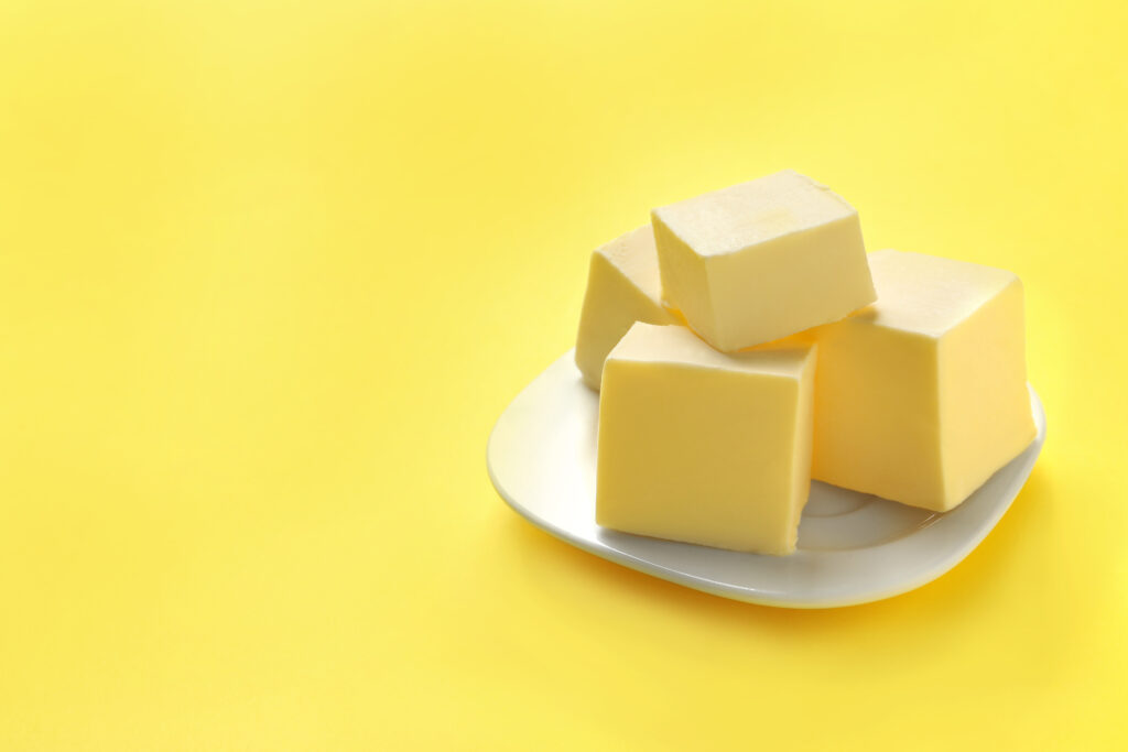 Blocks of butter on a white plate against a yellow background.