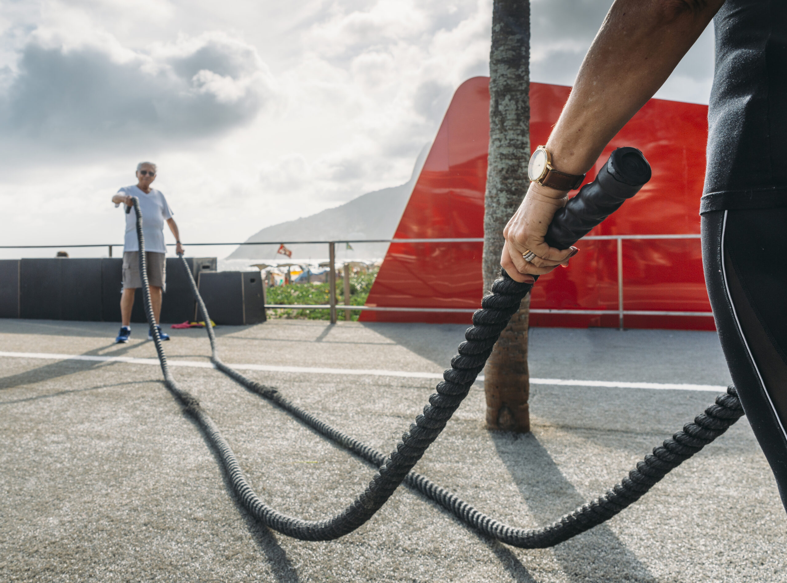 People exercising with battle ropes in an outdoor workout area.