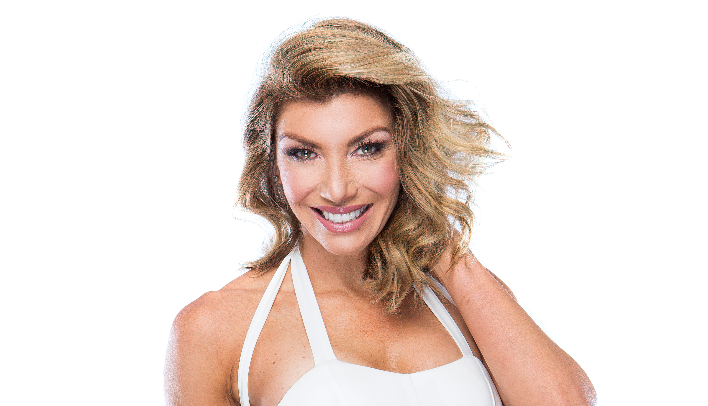 Smiling woman in a white halter top touching her hair.