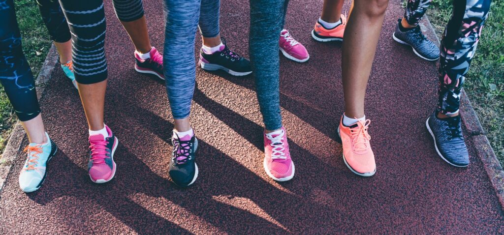 Six people standing on a running track wearing colorful athletic shoes and leggings.