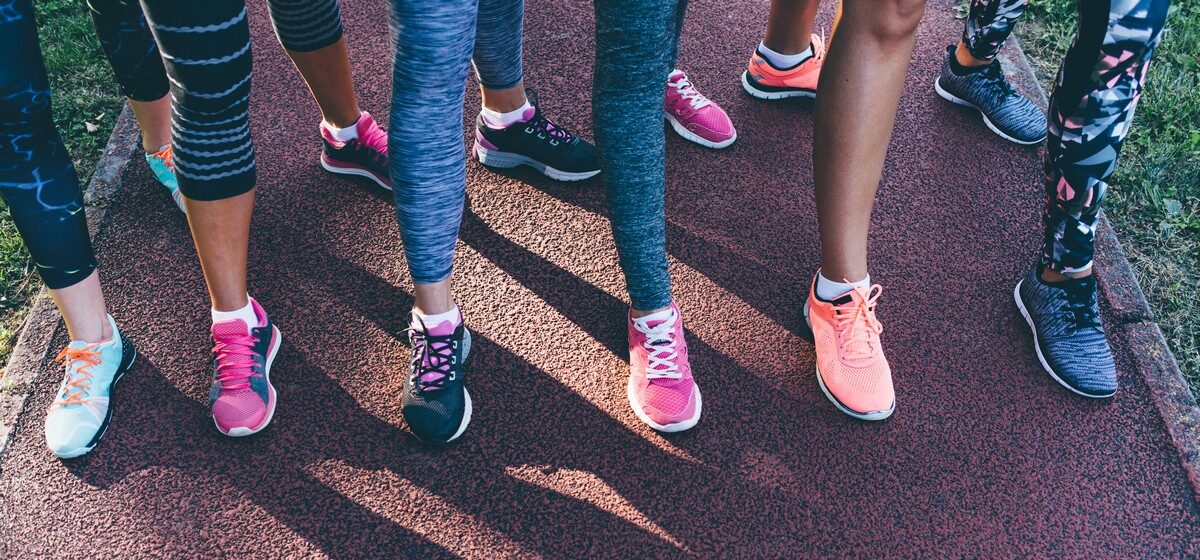 Six people standing on a running track wearing colorful athletic shoes and leggings.