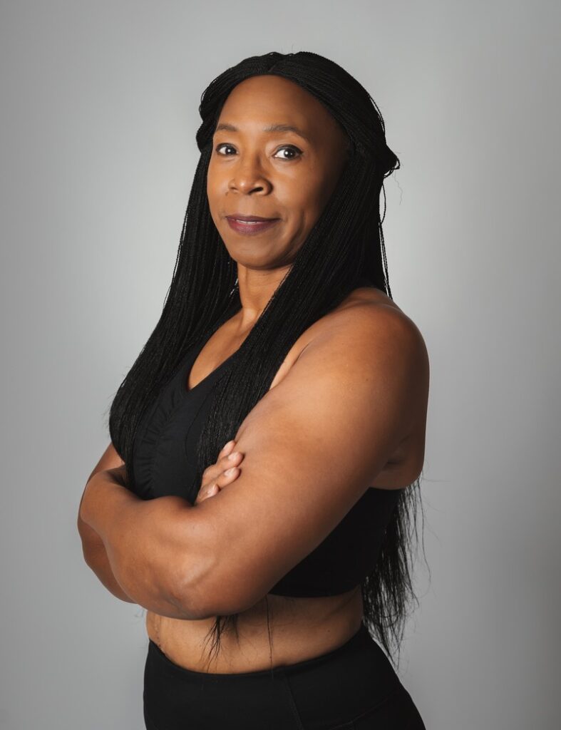 Portrait of a woman with long braids wearing a black sleeveless top.