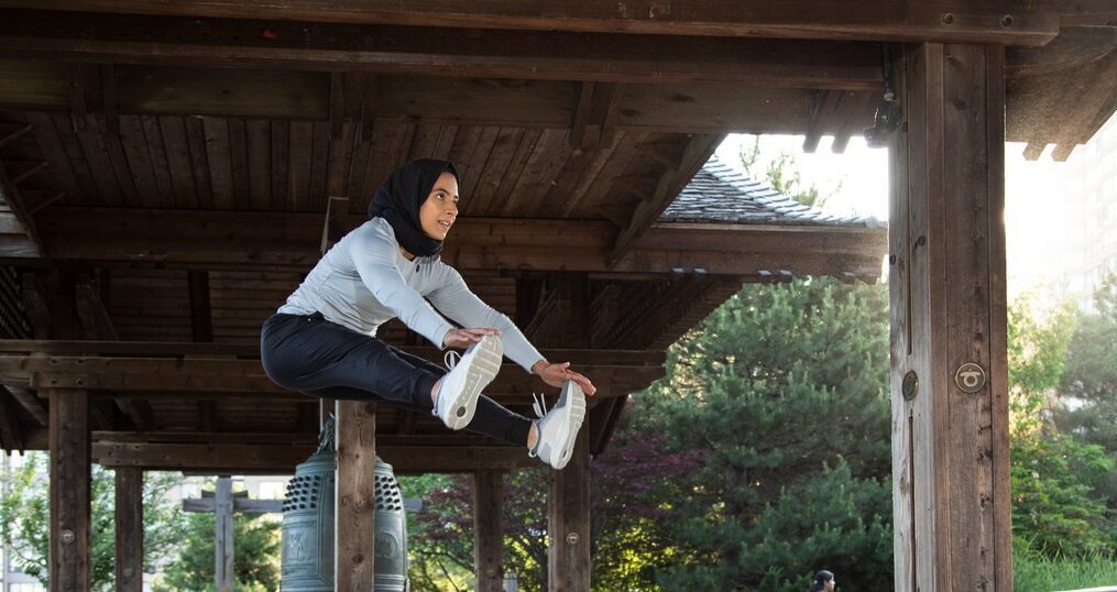 Woman performing a tuck jump with both knees drawn toward her chest.