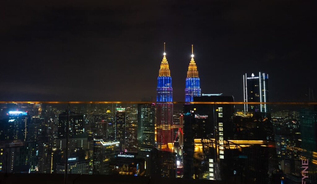 Night view of Kuala Lumpur city skyline with illuminated Petronas Twin Towers and surrounding buildings.