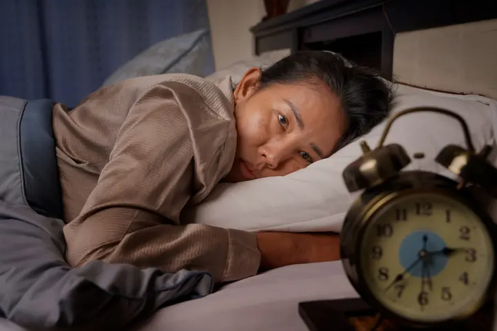 Person lying awake in bed with eyes open, looking at an alarm clock showing 3:35.